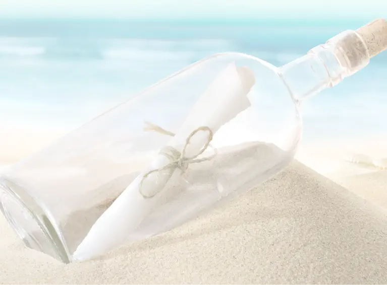 A glass bottle with a message inside on sand
